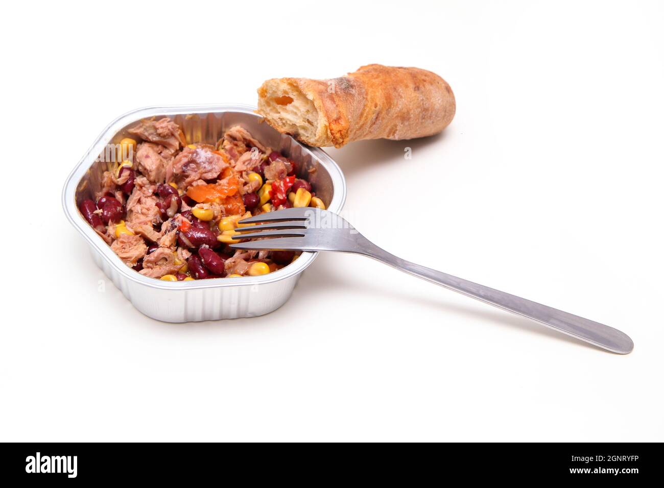 The ready to eat tuna salat with vegetables in the aluminium tub with a fork and piece of bakery isolated in a white background. Stock Photo