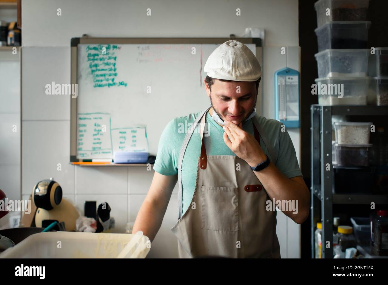 A young man in a cap and apron at the baker's job. Problem solving concept. Stock Photo
