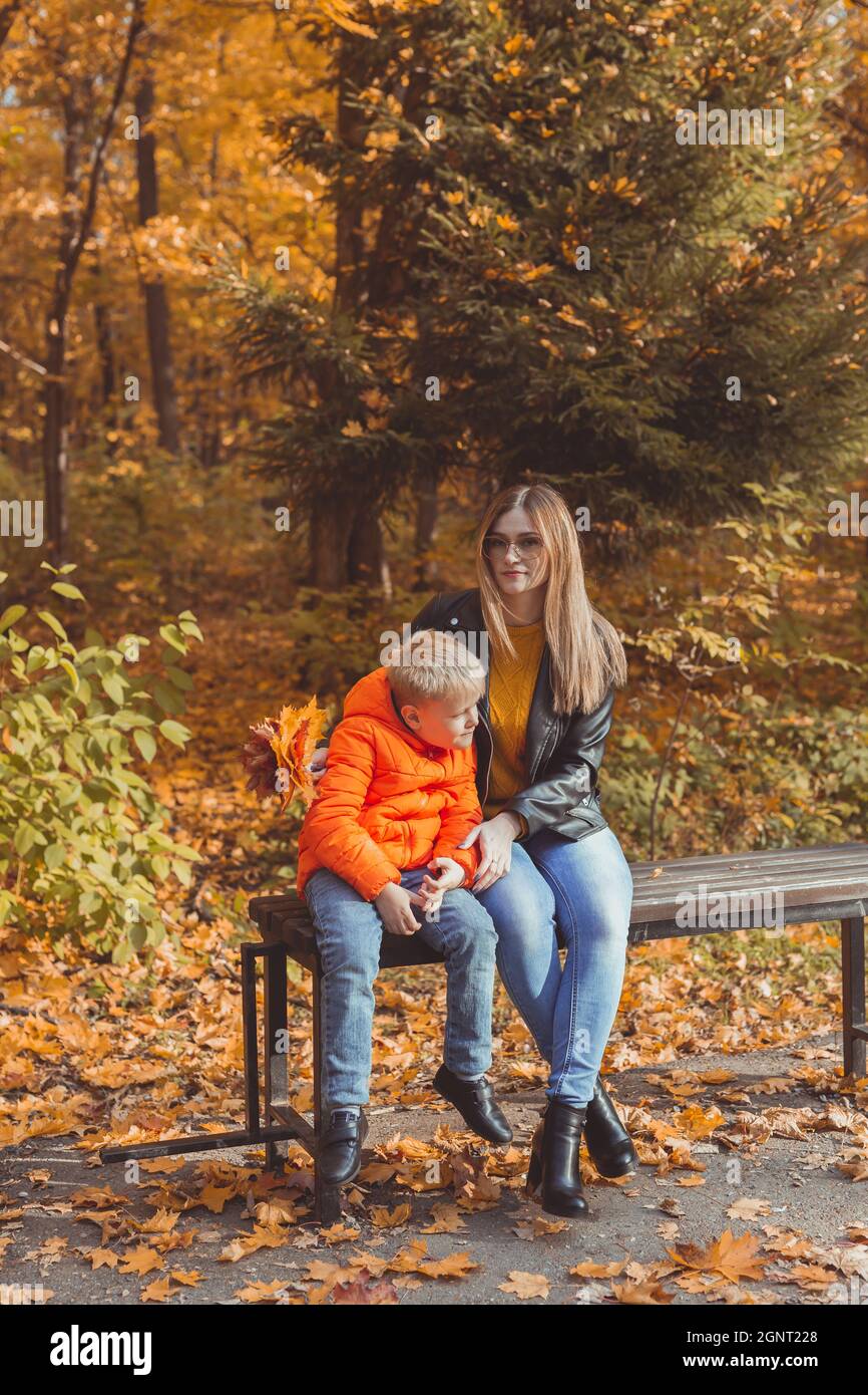 Single parent mother and child boy in the autumn in park sit on bench ...