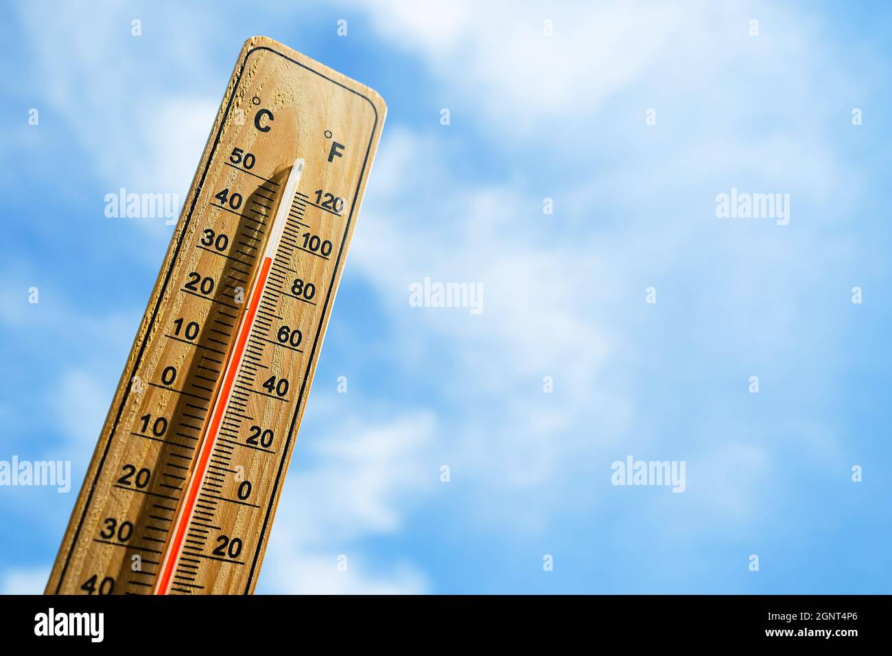 Wooden thermometer with red measuring liquid showing high temperature over  32 degrees Celsius on background of blue sky with clouds. Concept of heat w  Stock Photo - Alamy