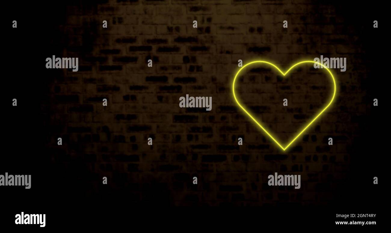 Image of yellow neon heart flashing on dark brick wall Stock Photo