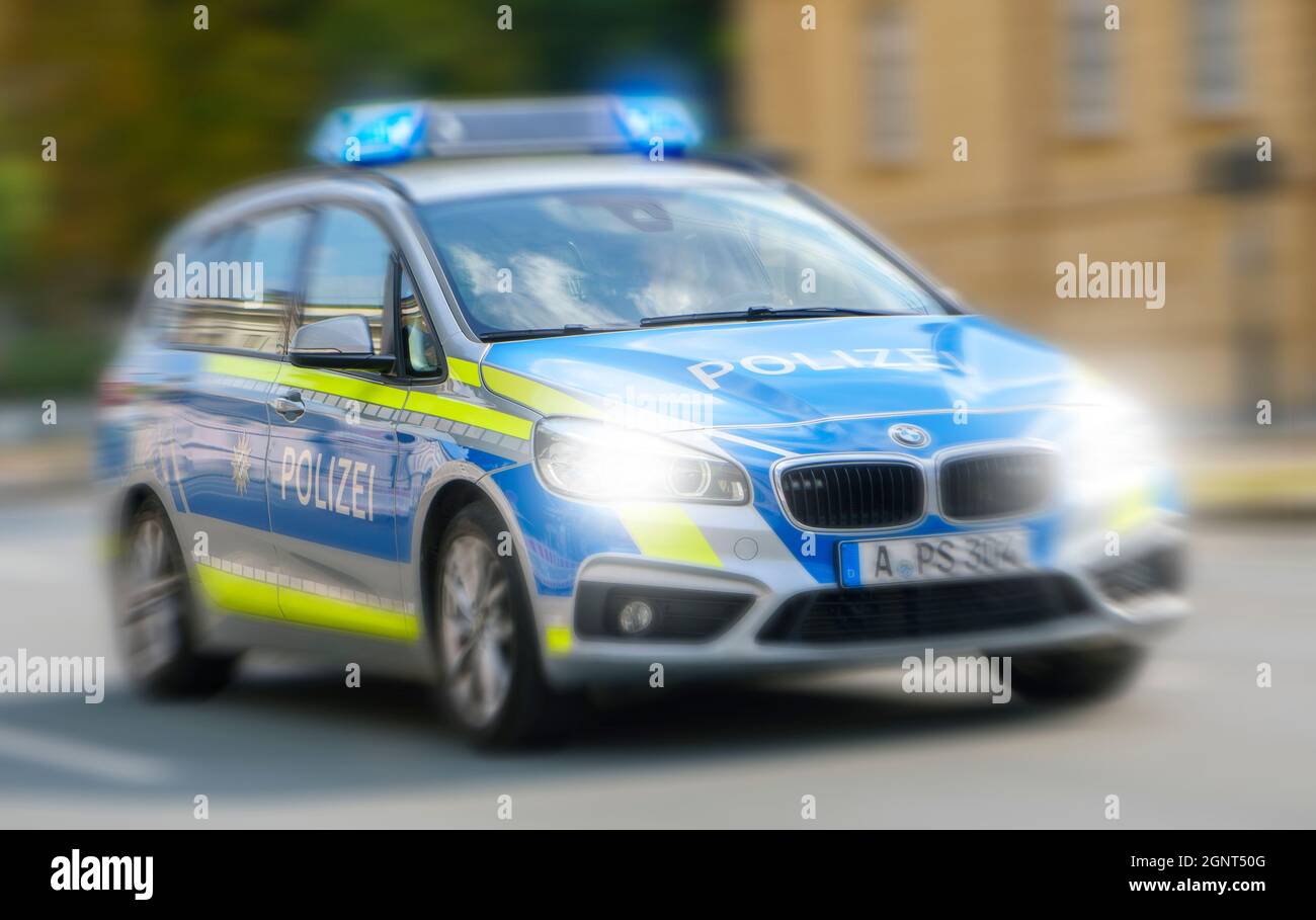 Ein Polizeiauto fährt mit hoher Geschwindigkeit und Blaulicht durch die Stadt Augsburg Stock Photo