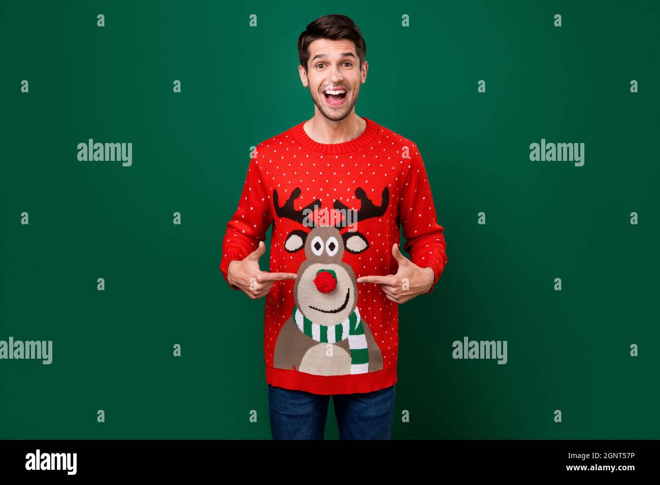 Photo of young man happy smile point finger reindeer nose ball jumper christmas atmosphere isolated over green color background Stock Photo