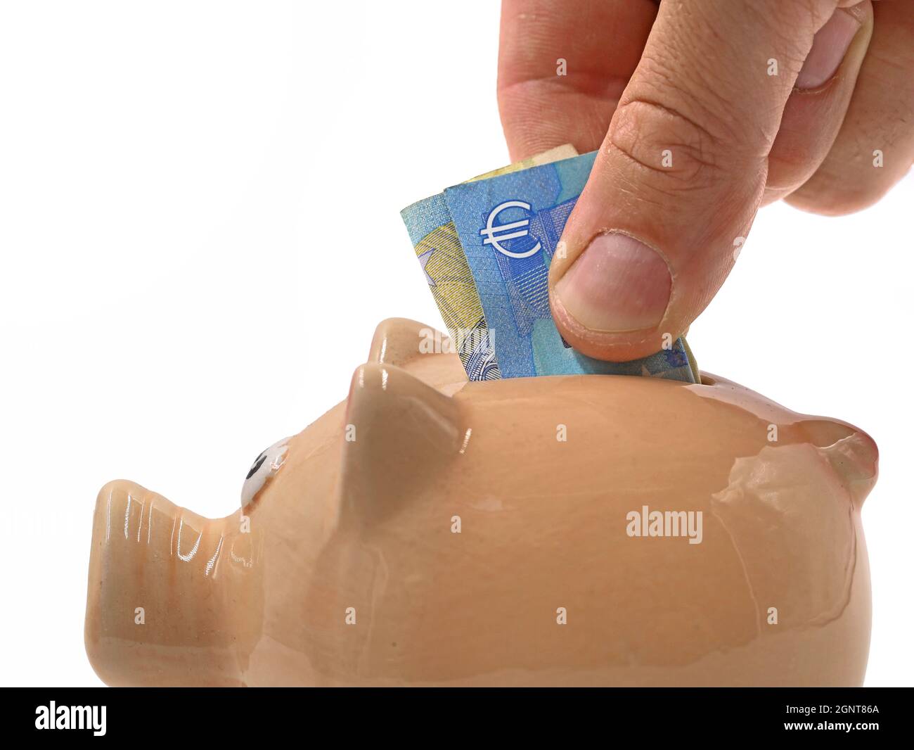 close up of male hand putting euro banknote in piggy bank, saving money concept image isolated on white background Stock Photo