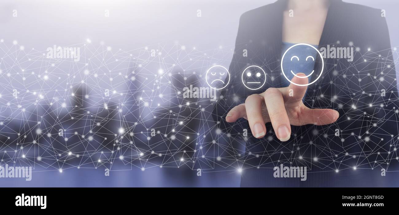 Review, Rating,Satisfaction. Hand touch digital screen hologram Smiley Face sign on city light blurred background. Business satisfaction survey. Smile Stock Photo