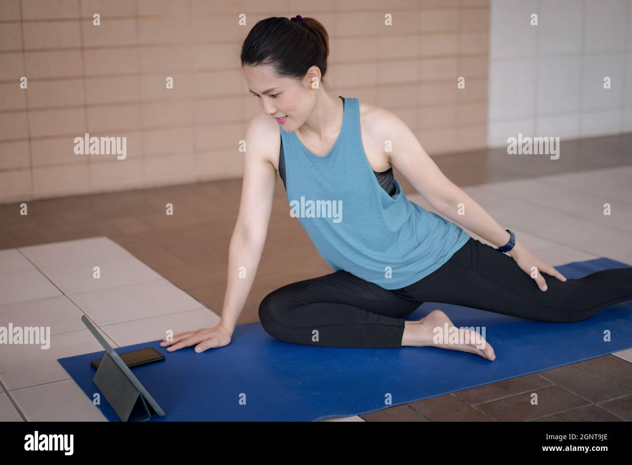 een beetje langs helaas South Asian woman in a sports outfit watching an online workout program via  tablet in the home Stock Photo - Alamy