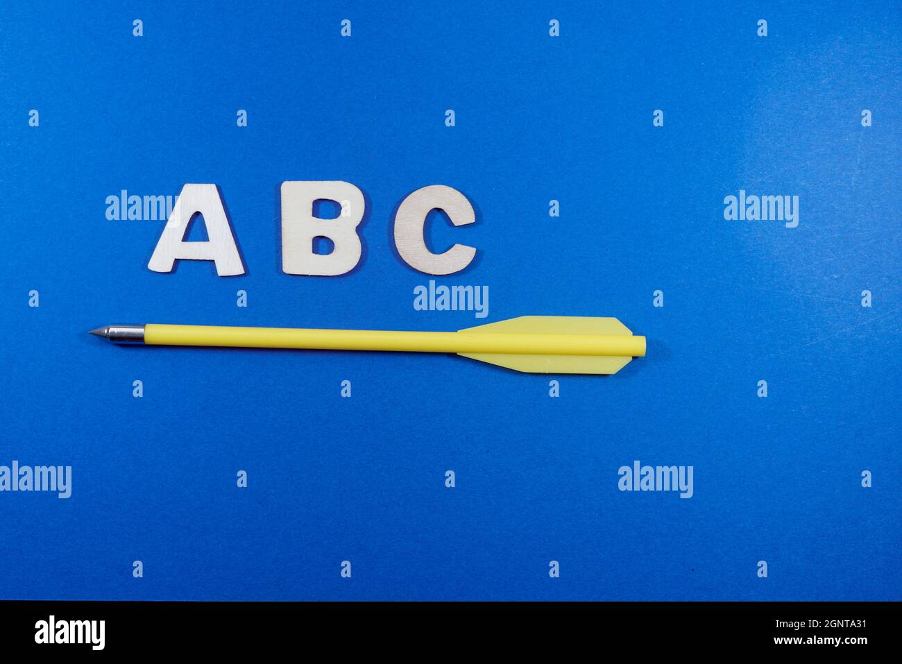 Closeup shot of a yellow pen body under the A B C writing on a blue surface Stock Photo
