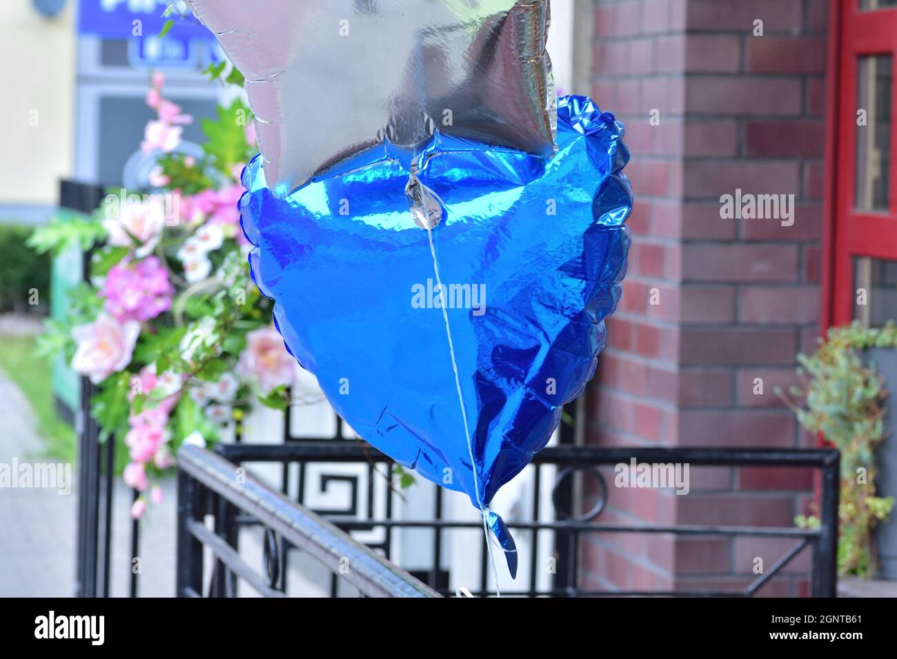 A silver and blue balloon tied to a metal railing against the background of traffic. Bokeh. Stock Photo
