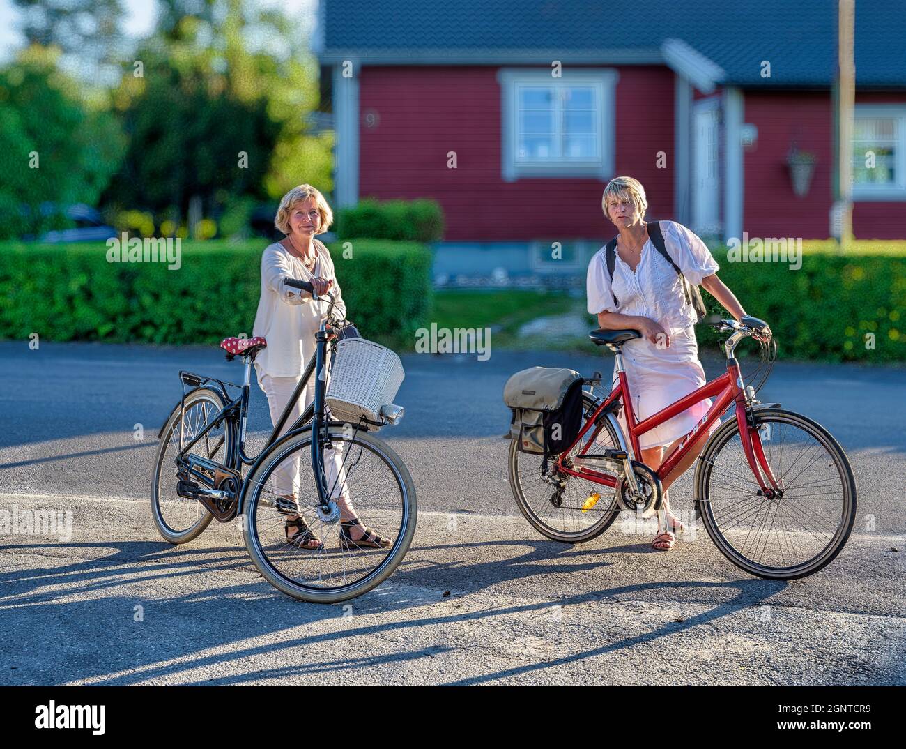 Two women taking a break during an evening ride on bicycles Stock Photo