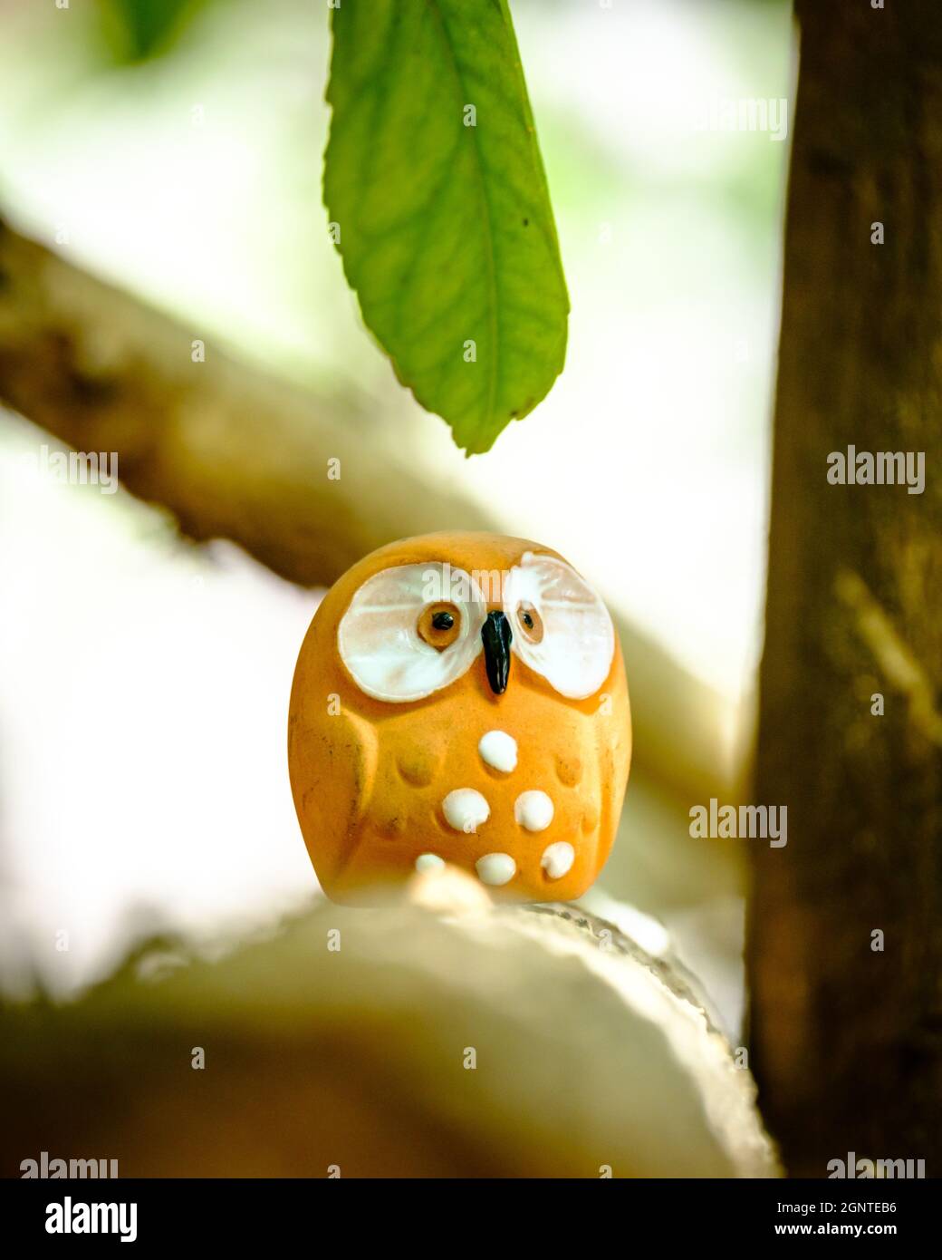 shot of an orange owl figure amongst the trees Stock Photo