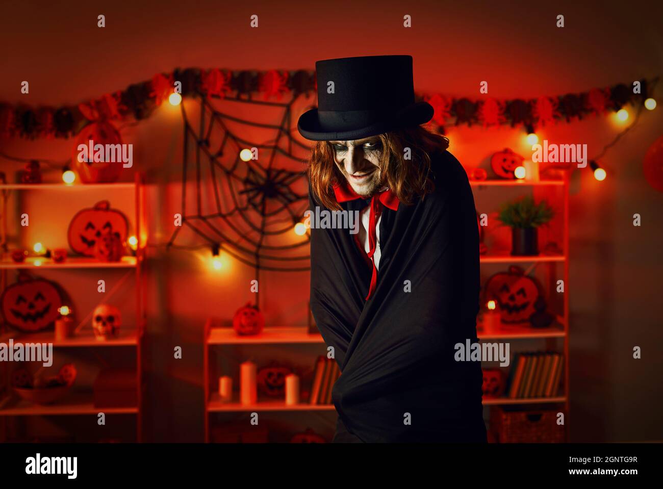 Man dressed up in top hat and cloak to look like evil vampire at Halloween horror party Stock Photo