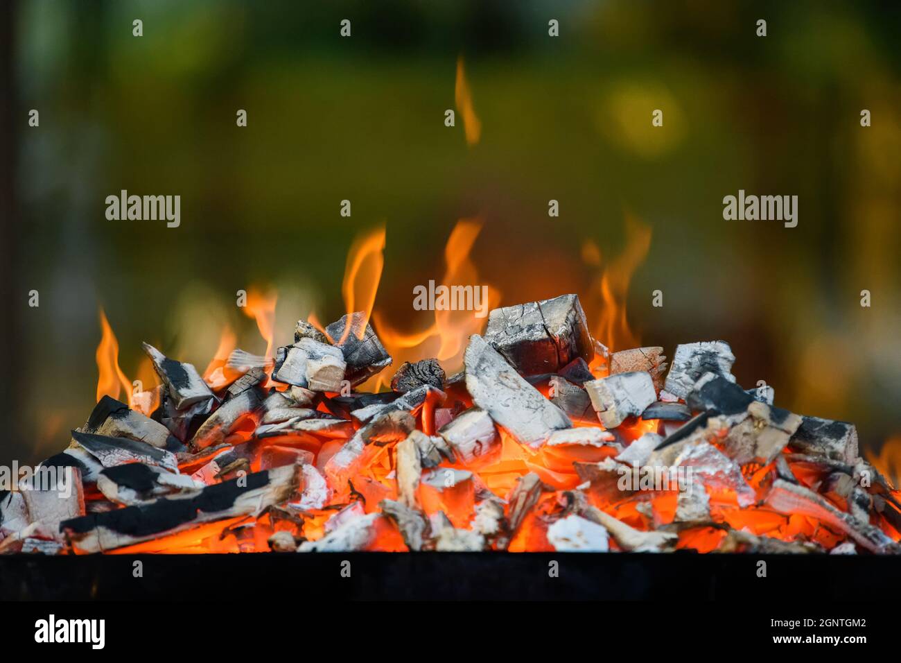Closeup barbecue grill pit with glowing and flaming hot charcoal