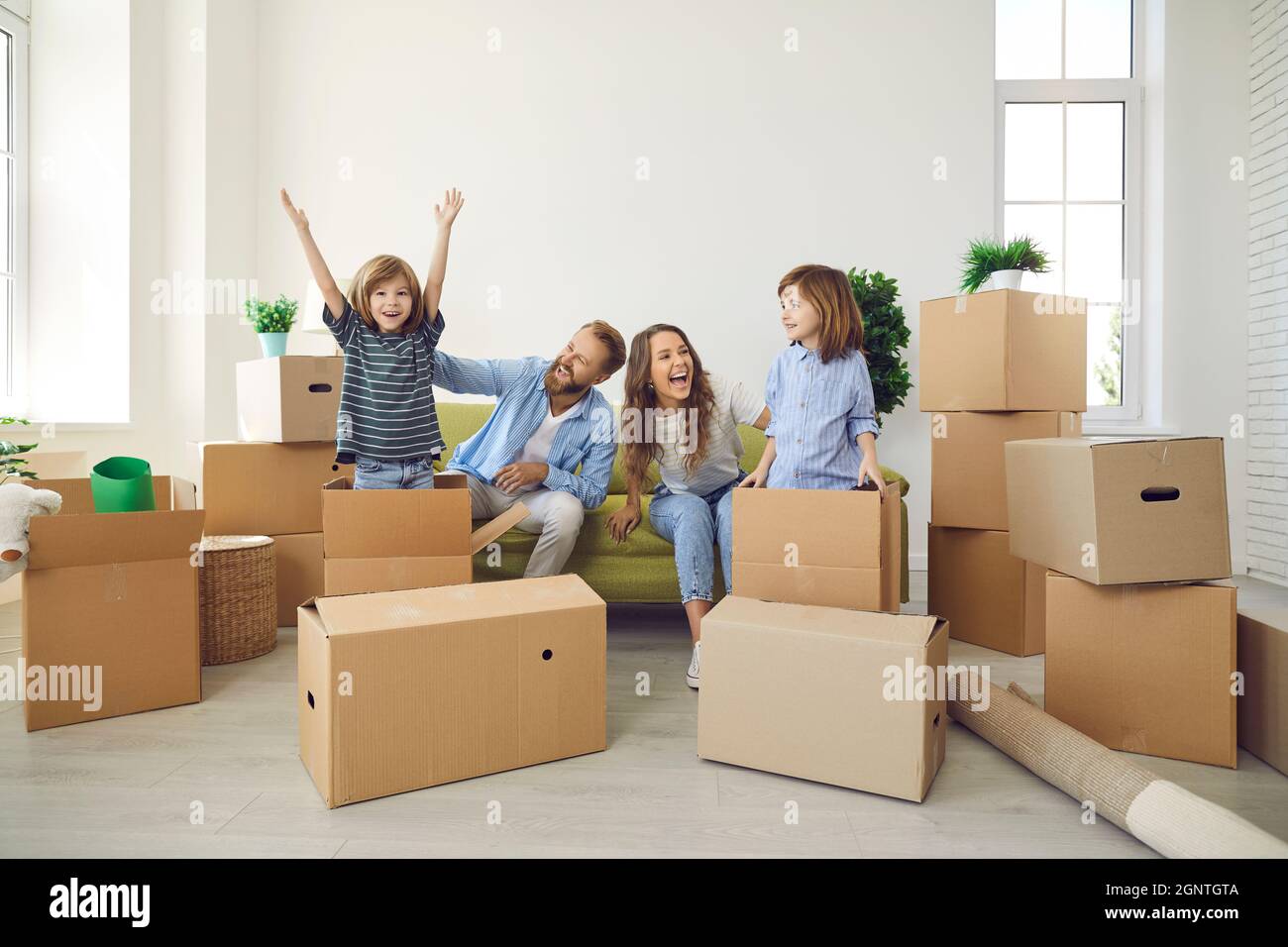 Happy young family playing with cardboard boxes and having fun in their new home Stock Photo