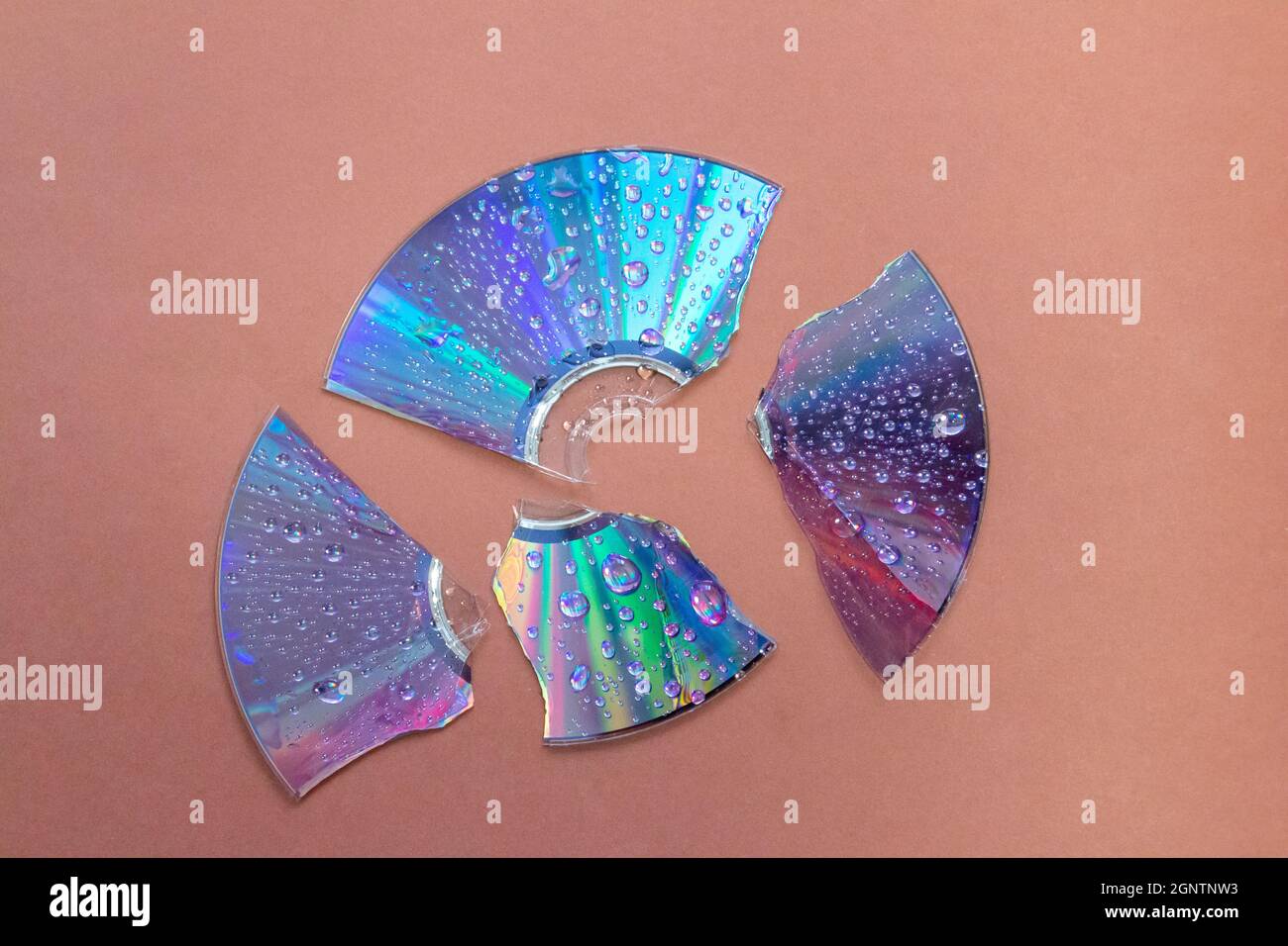 broken retro CD disc with wet drops against brown background Stock Photo