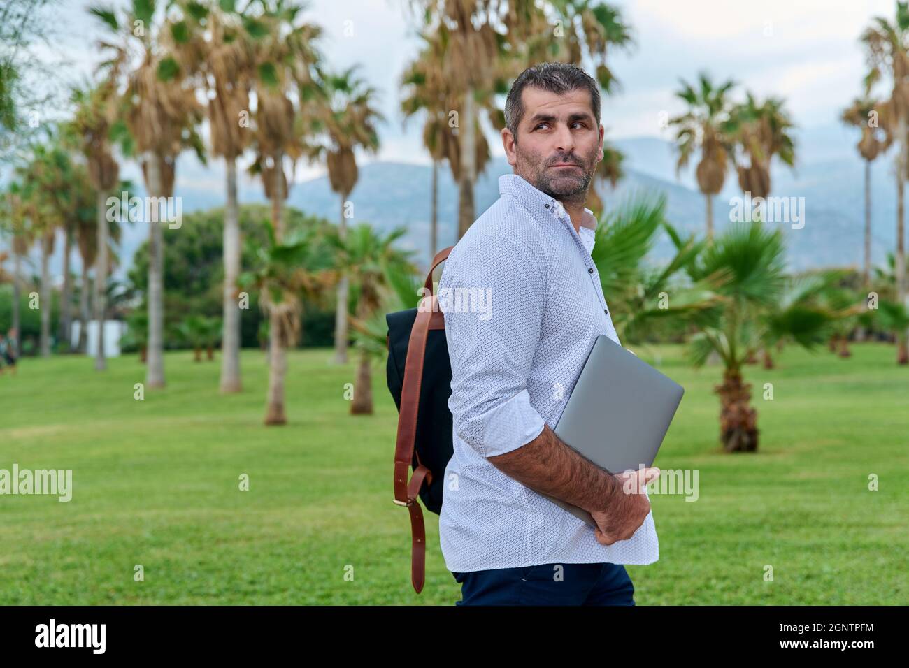 Portrait of serious confident mature man with laptop outdoors Stock Photo