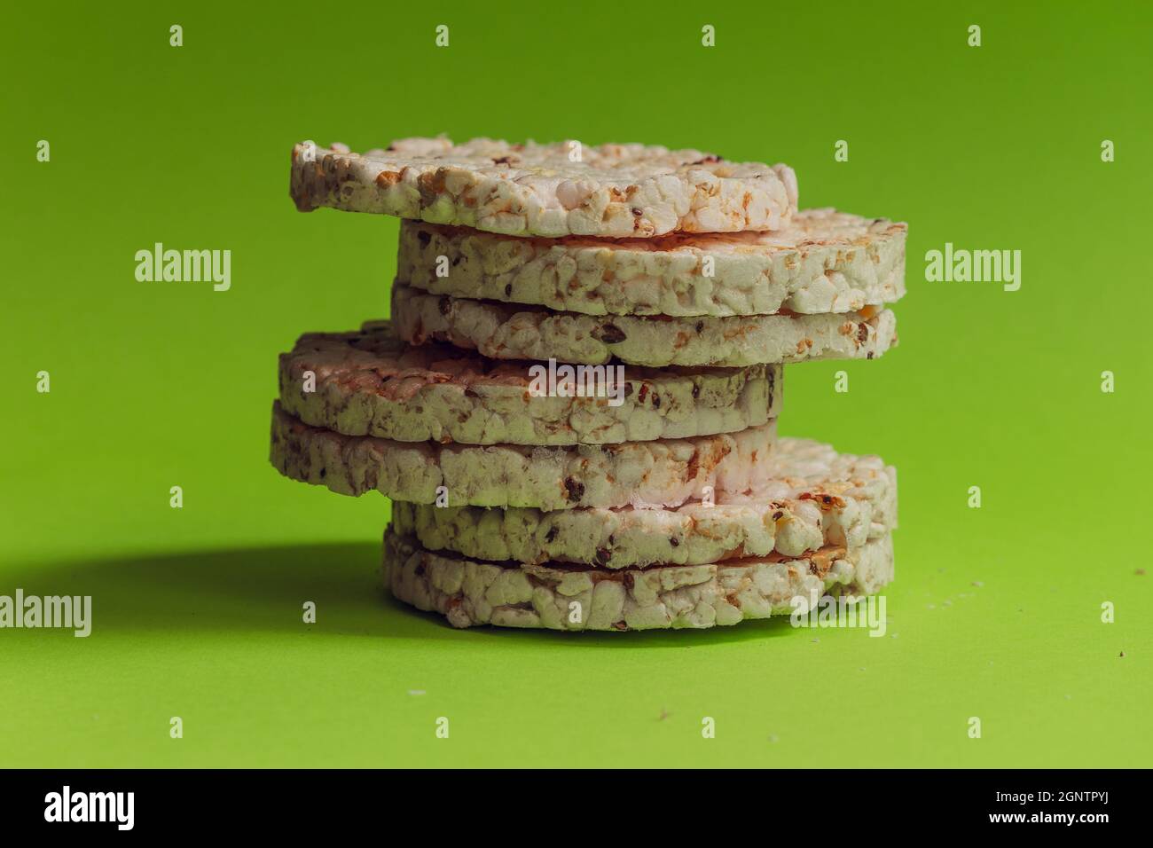 Seven round healthy breads stand in a column against a bright green background. Stock Photo