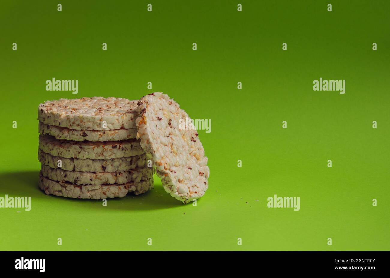 Rice cakes with grains stand in a column against a bright green background. Stock Photo