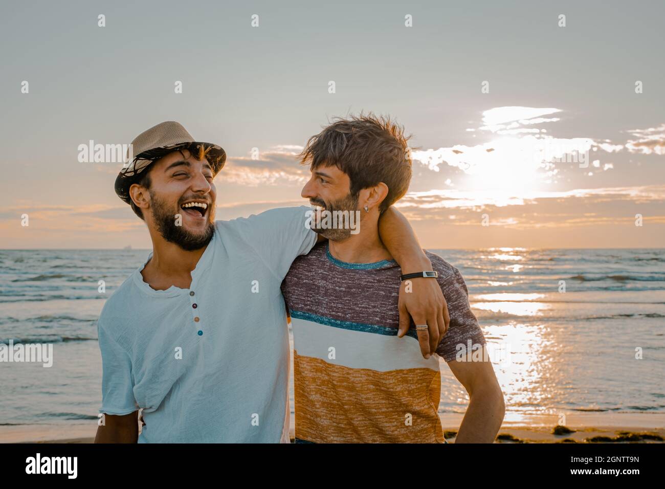 Two friends hug each other at the sunset on the beach. Friendship and love concept Stock Photo