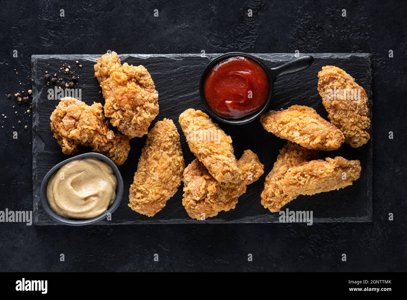 Spicy deep fried chicken wings with sauces served on black slate
