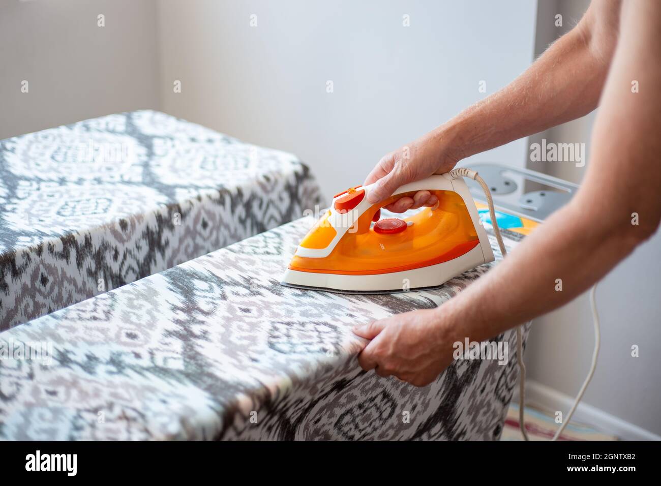 A man with an iron in his hands ironing linen on an ironing board