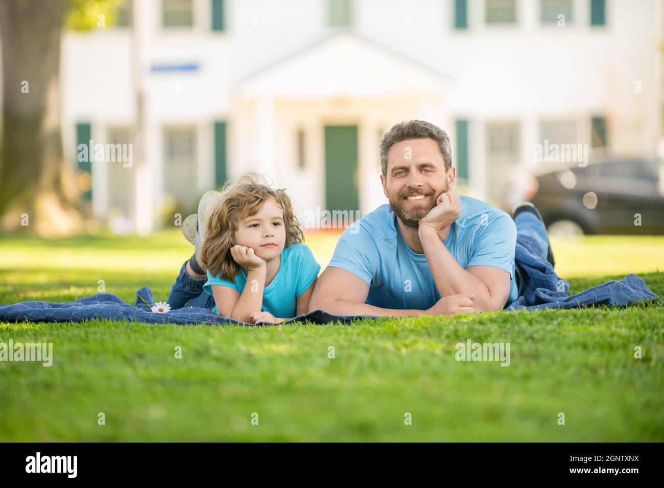 cheerful father with child relax together on green park grass, parenthood Stock Photo
