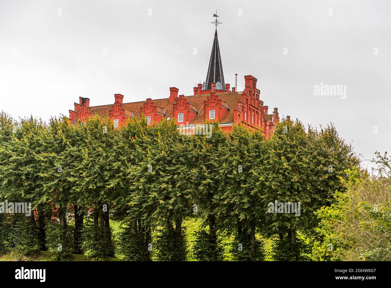 Tranekær Castle is glowing red in the park. The castle has existed on this site since the 13th century and was used as an official residence by the officials of the Danish king on the island of Langeland, Denmark Stock Photo