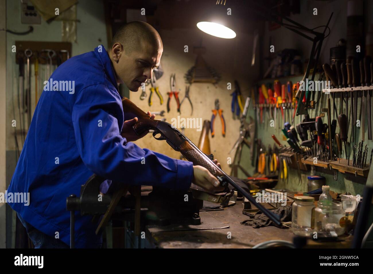 Gunsmith performing checkout of singlebarrelled shotgun in weapons