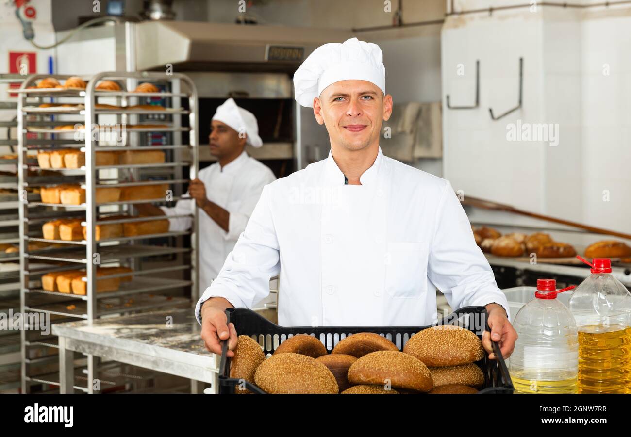 Male baker carrying crate with baked bread Stock Photo - Alamy