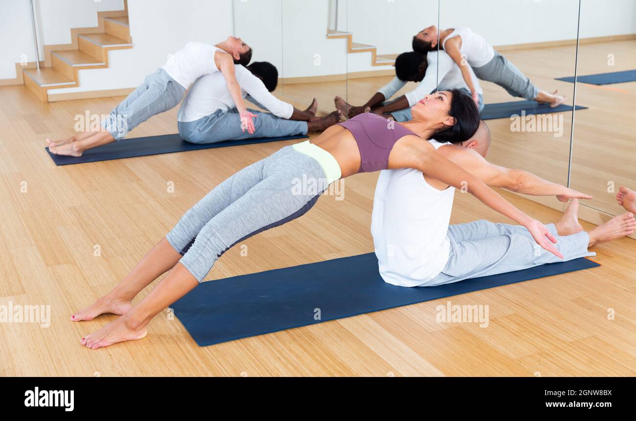 Couples practicing yoga with partner at studio Stock Photo