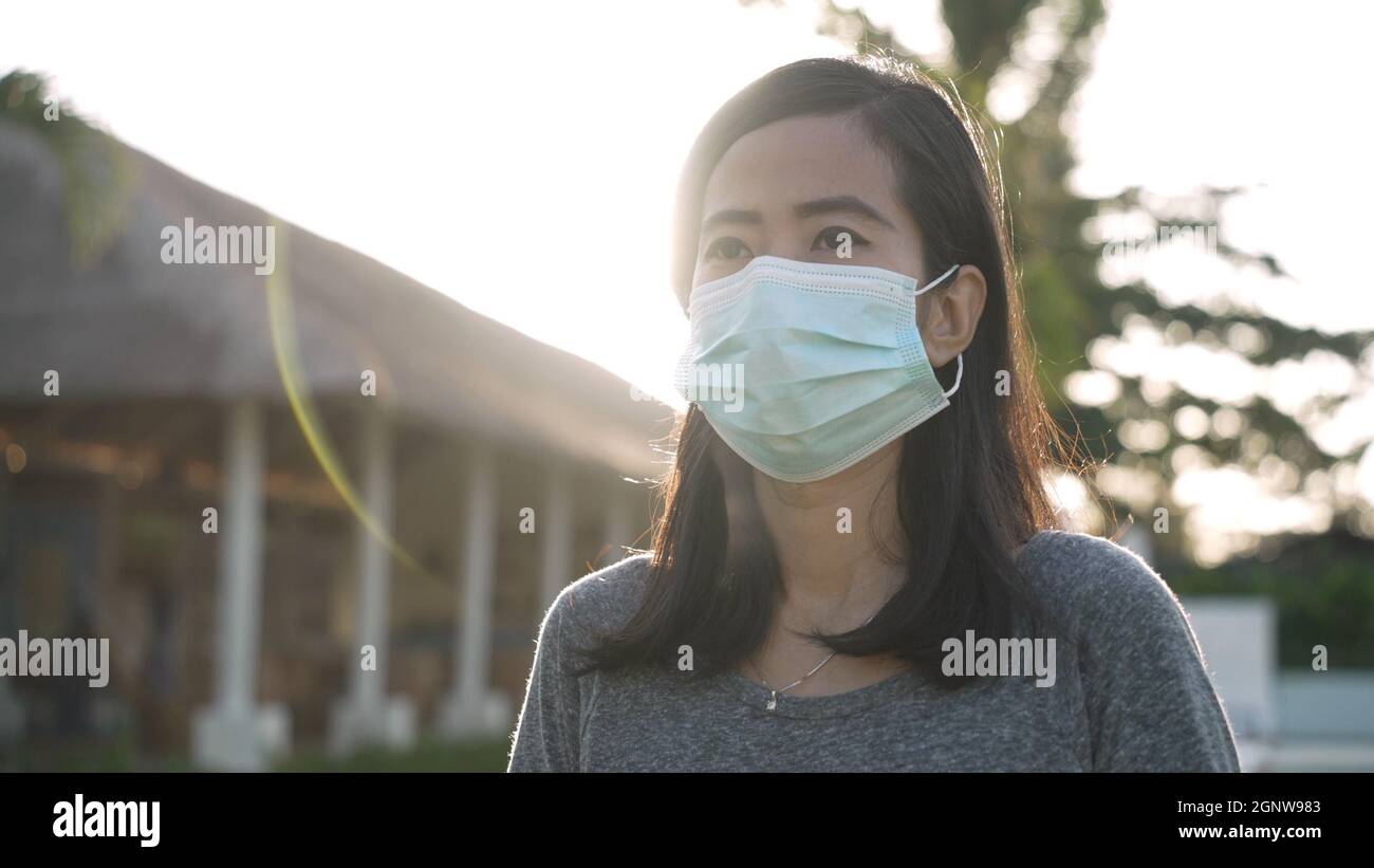 Coronavirus. Asian woman putting on a medical disposable mask to avoid ...