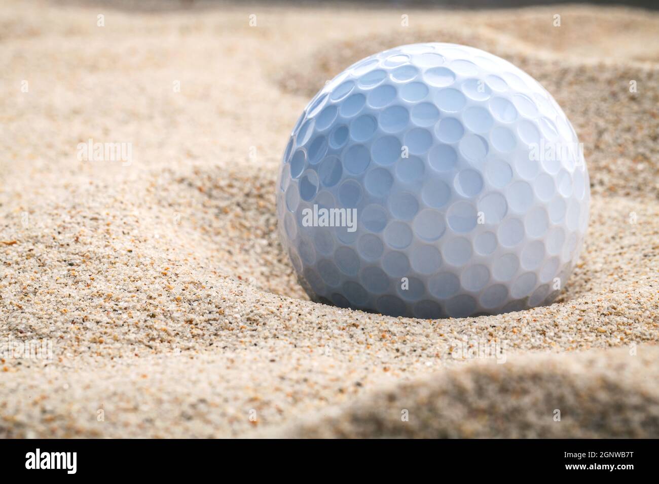 Close up golf ball in sand bunker shallow depth of field. A golf ball