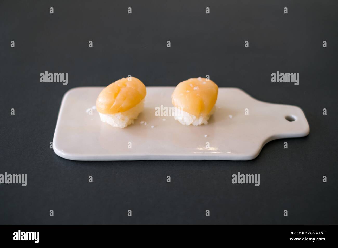 Two Nigiri Sushi With Scallop Served On Beige Board Two Sushi Pieces