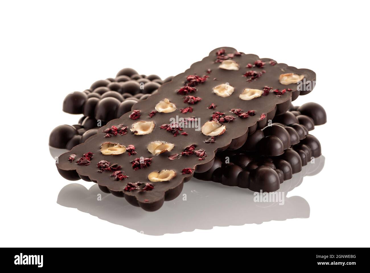 Dark raw chocolate with haselnut and freeze-dried cherries on a white background. Isolate Stock Photo