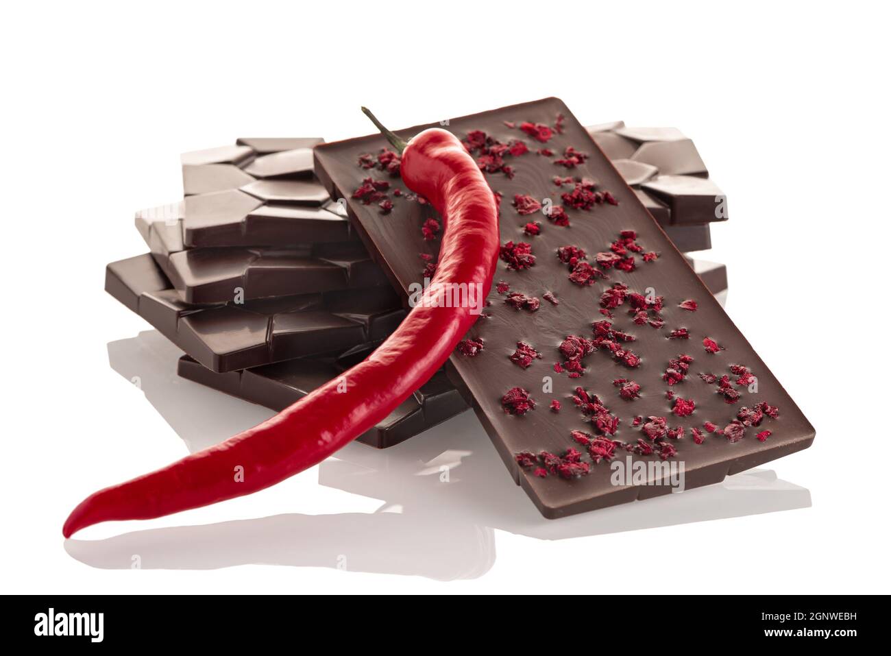 Dark raw chocolate with chili pepper and freeze-dried cherries on a white background. Stock Photo