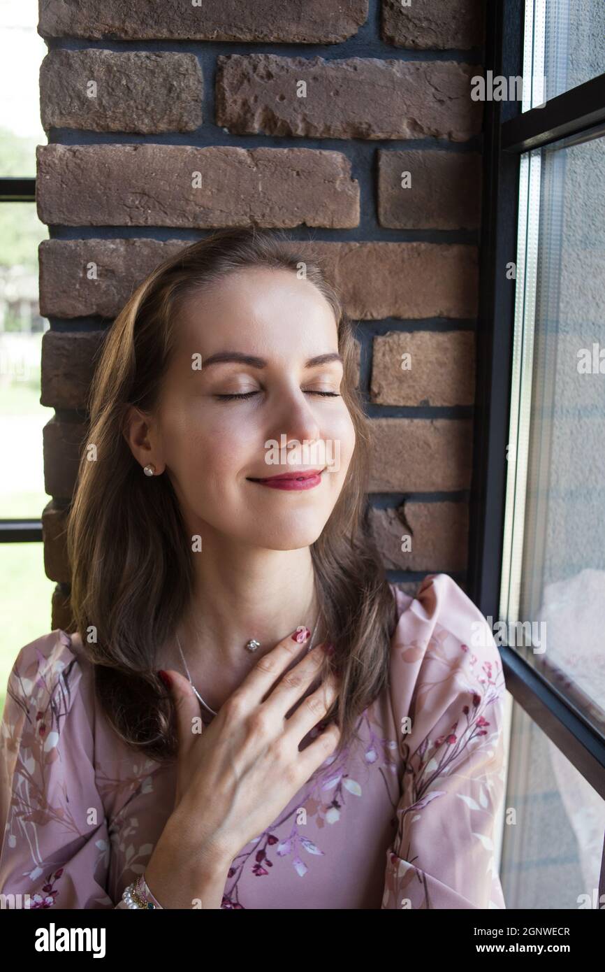 Beautiful young woman in pink dress sits on the windowsill Stock Photo ...