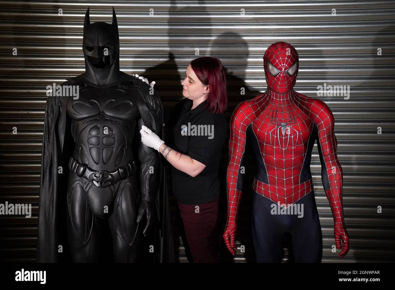 A Prop Store employee adjusts Val Kilmer's Sonar Batsuit from 1995 film ' Batman Forever' (est: £40,000 - 60,000) next to Tobey Maguire's production  made costume from 2007 film 'Spider-Man 3'(est: £30,000 -