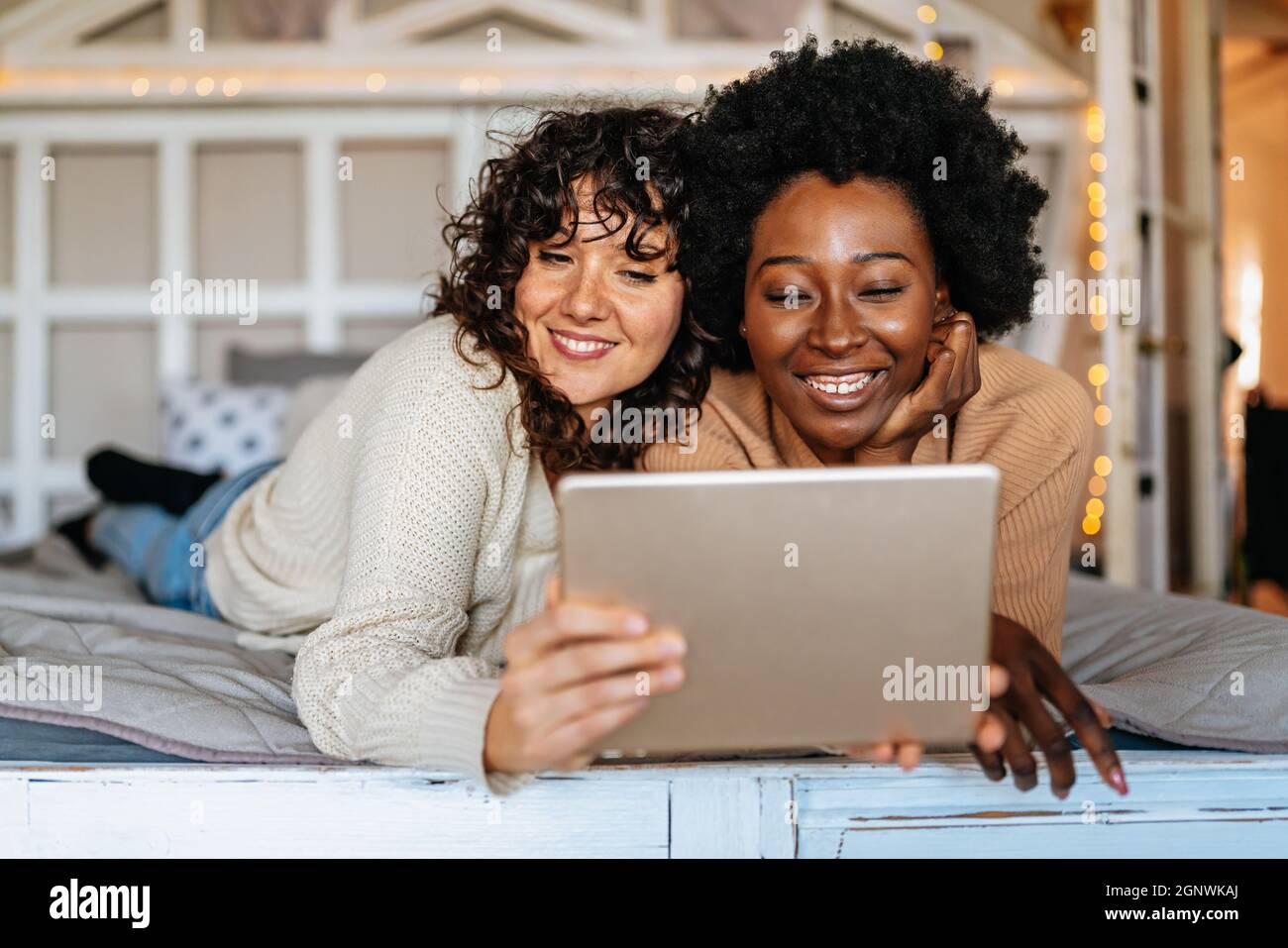Beautiful happy gay couple having fun and good time together with tablet at home Stock Photo