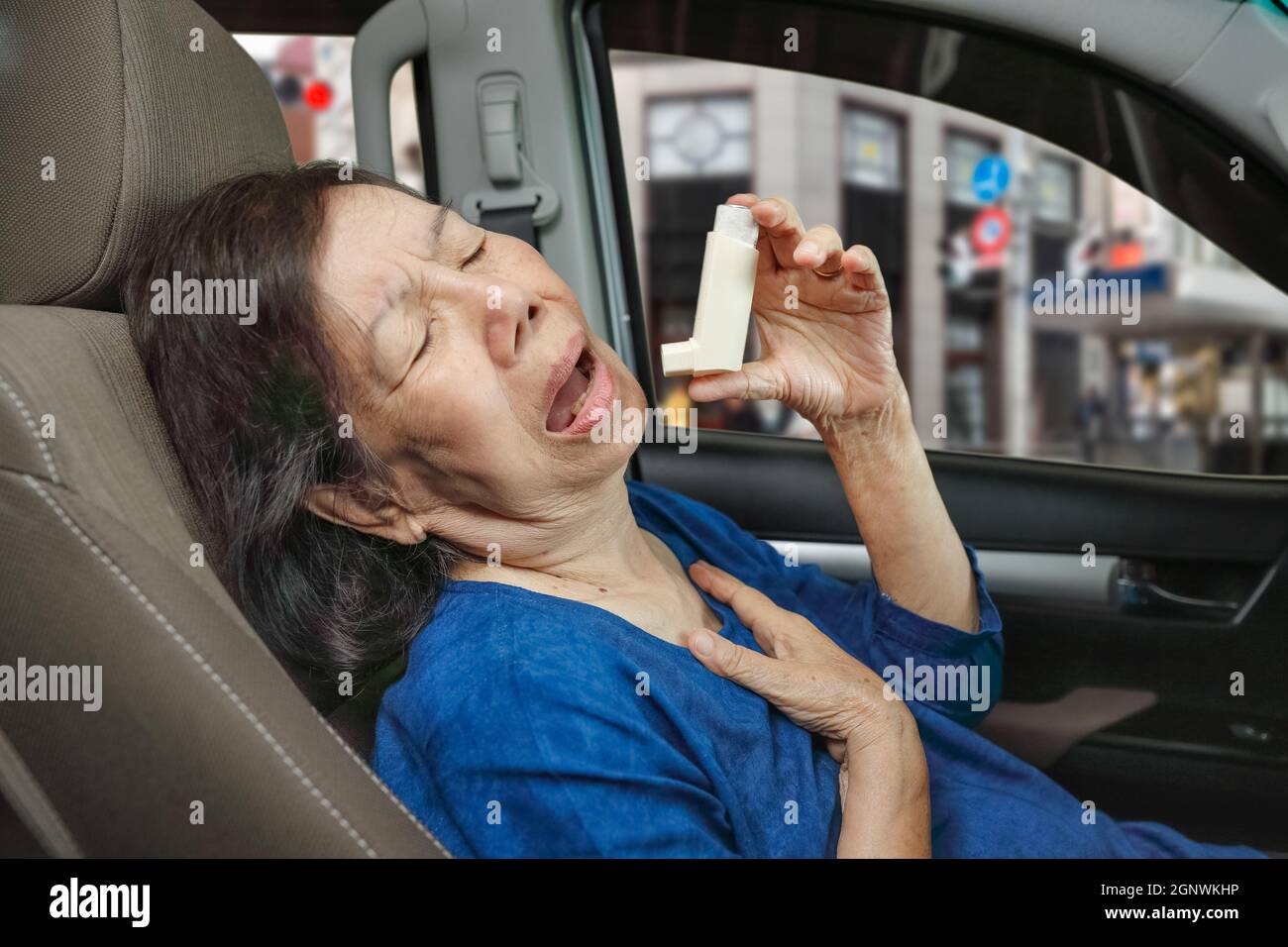 Elderly woman choking and holding an asthma spray inside car on the way