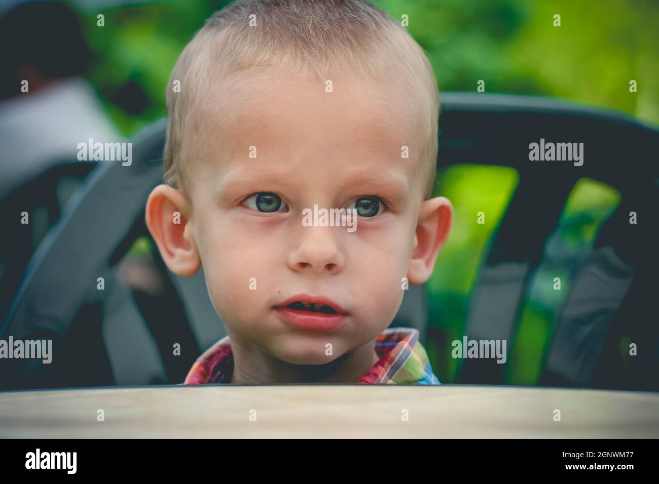 One year old baby boy seat at the outdoor table and wait for dinner