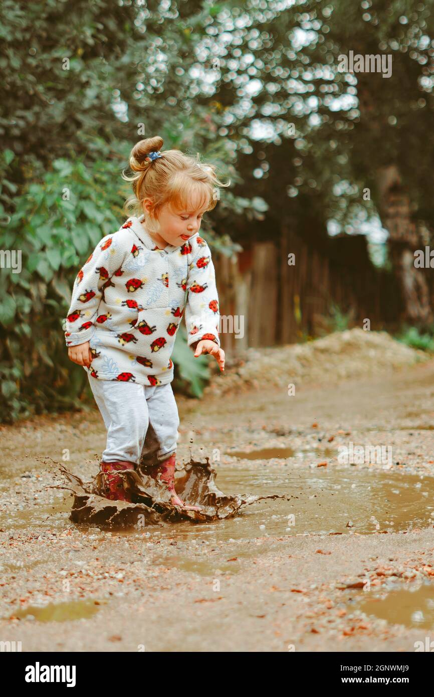 a child runs through puddles in rubber boots Stock Photo - Alamy