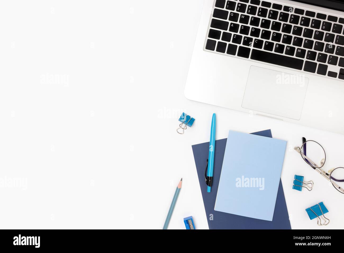 Laptop and blue office supplies on a white background. Workspace for