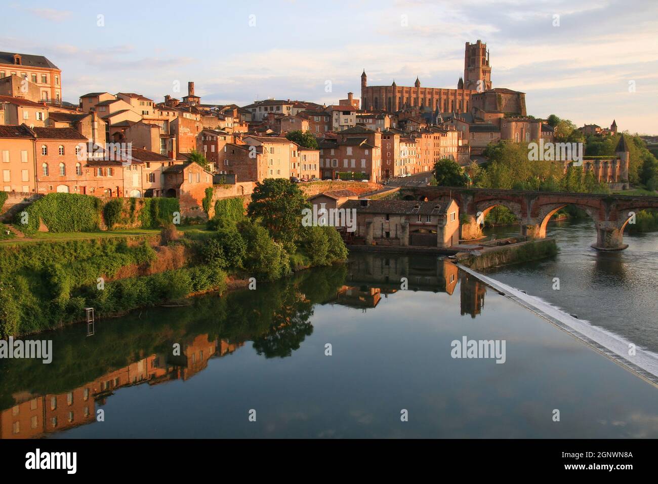 Cathedral St Cecile and reflections of the town in the River Tarn glowing red soon before sunset in Albi, Tarn, Occitanie, France Stock Photo