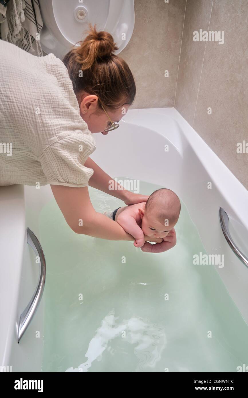 Mom and son are engaged in infant swimming in the home bathroom. A