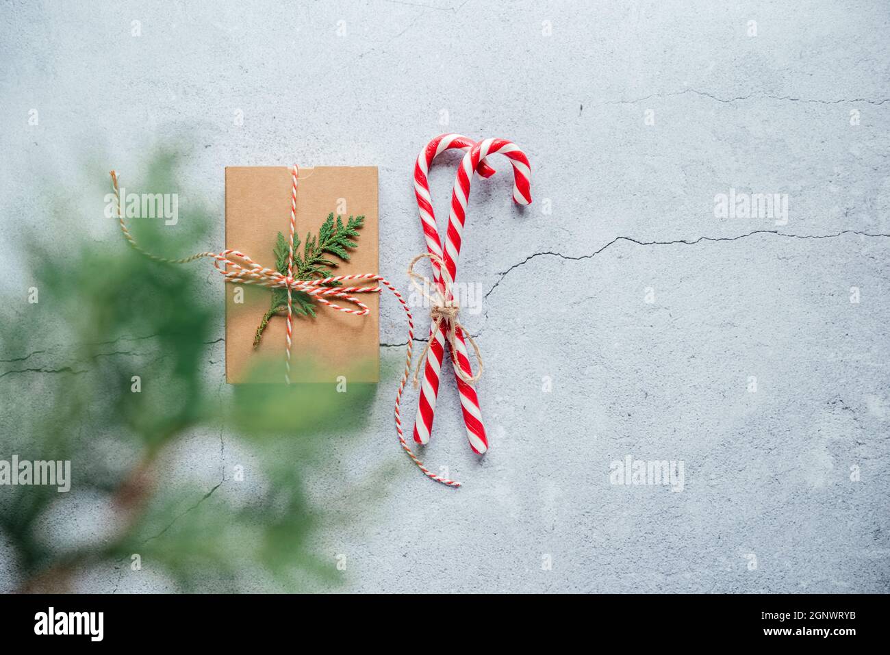 New Year composition with Christmas gift box, pine cones, and thuja branches on gray cement background with copy space Stock Photo