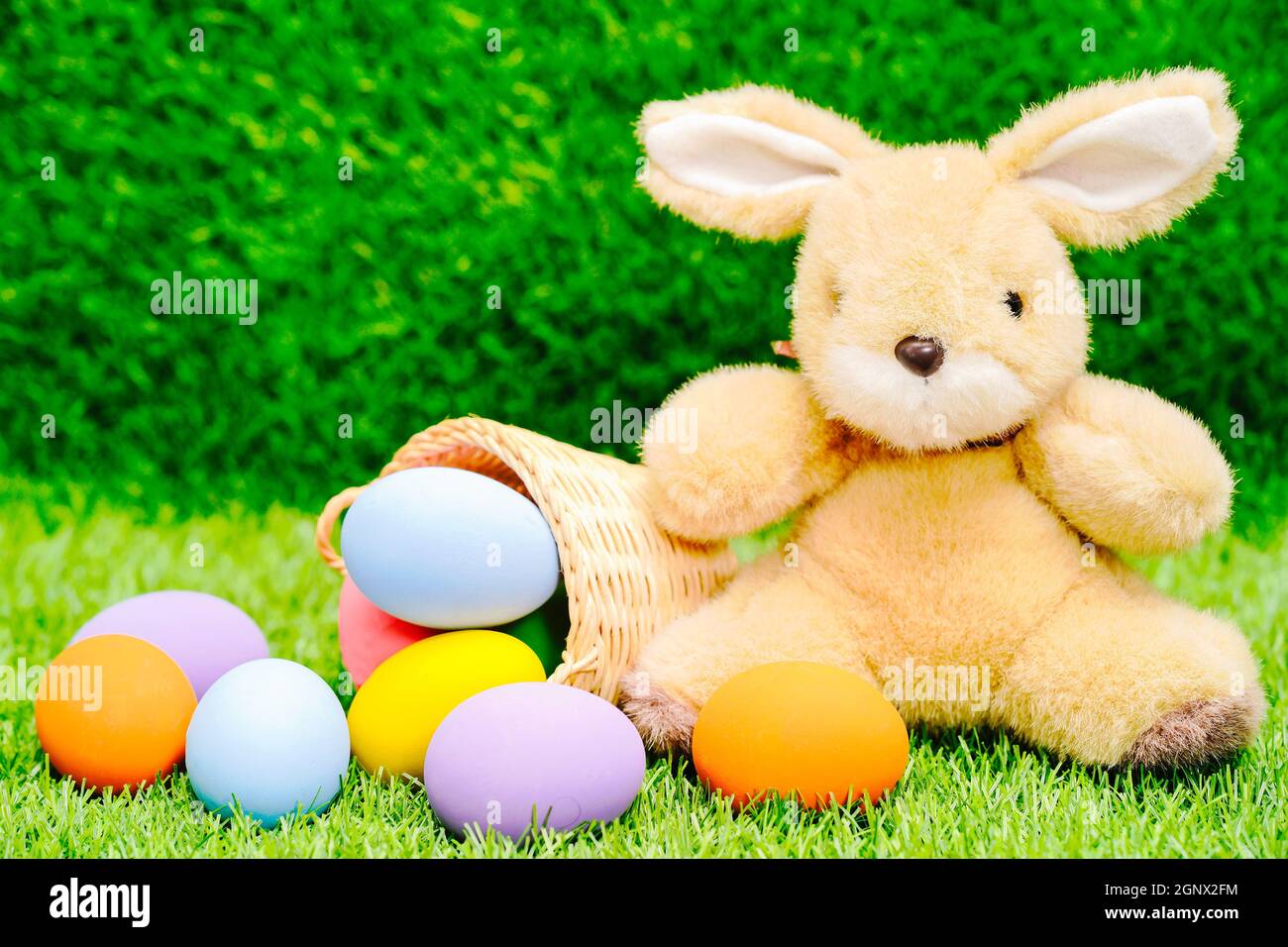 Easter bunny toy and Easter eggs in basket on green grass Stock Photo ...