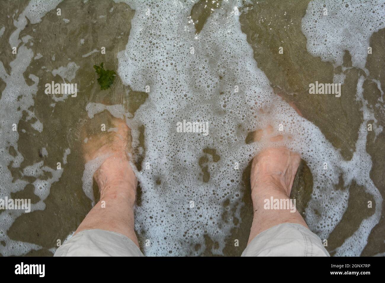 Barefoot in the water by the sea with a wave Stock Photo - Alamy