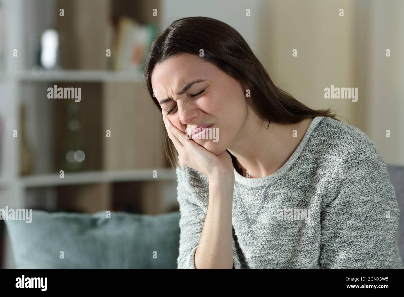 Stressed woman complaining suffering toothache sitting on a couch at home Stock Photo