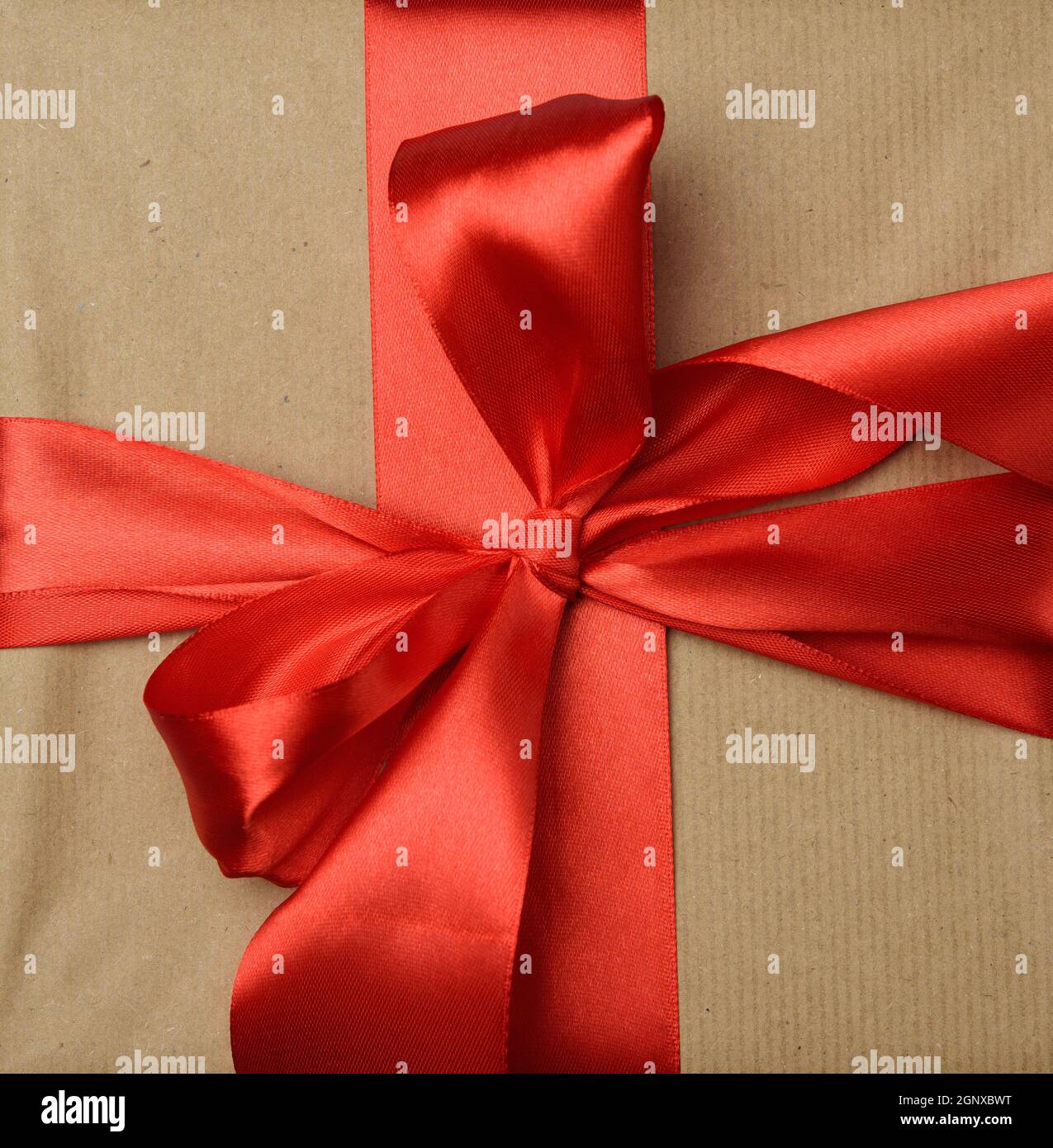 knotted red silk ribbon on brown kraft paper background, festive
