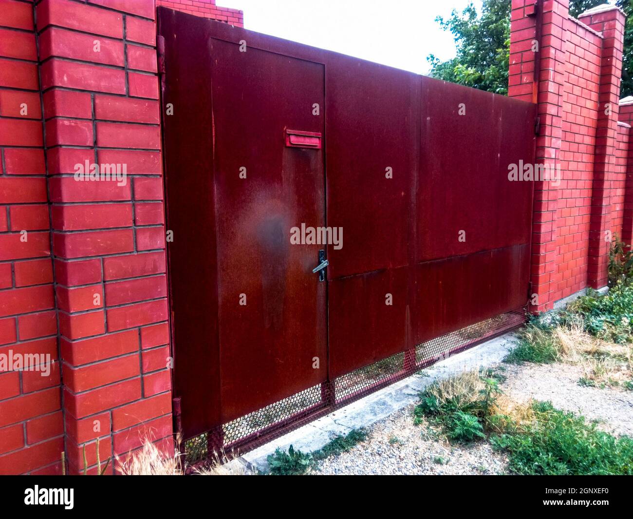 Steel rusty gates and a red brick fence Stock Photo - Alamy