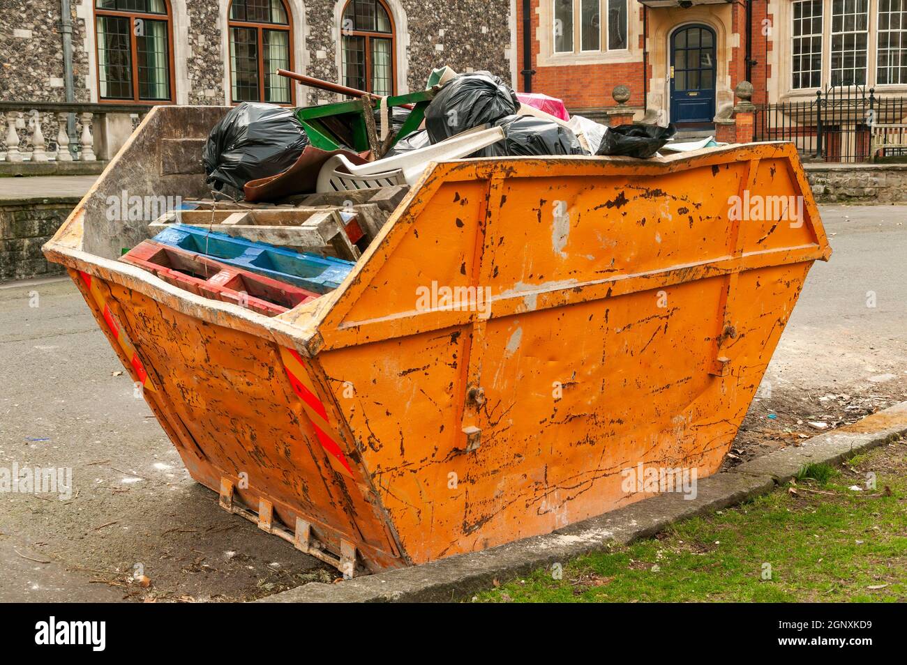 Heavy metal orange iron skip container full of scrap waste household